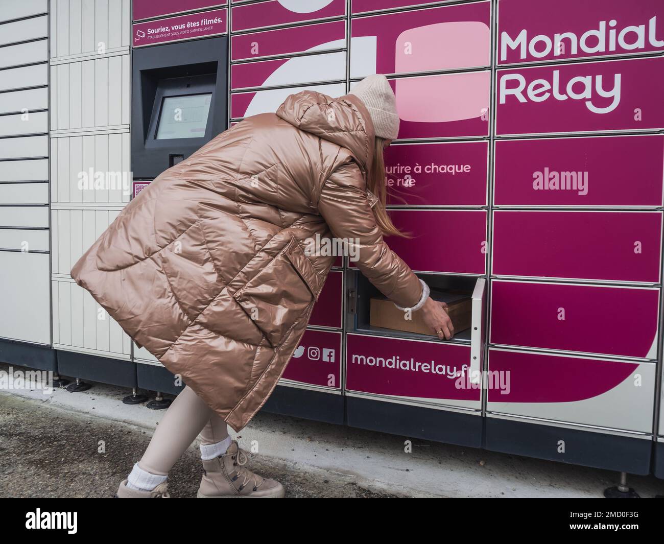 Loriol sur Drome, Frankreich - 14. Januar 2023: Abholung eines Pakets aus einem Mondial`Relay-Schließfach durch eine junge Frau. Schließfächer Mondial Relay. Pickup-Box. Stockfoto